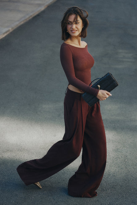 Image of woman in burgundy top and trouser.